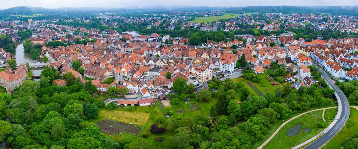 An aerial view of a town with a river, green spaces, and a mix of traditional and modern architecture.