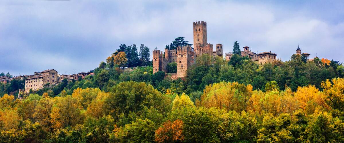 A historic castle on a hill surrounded by autumn-colored trees.