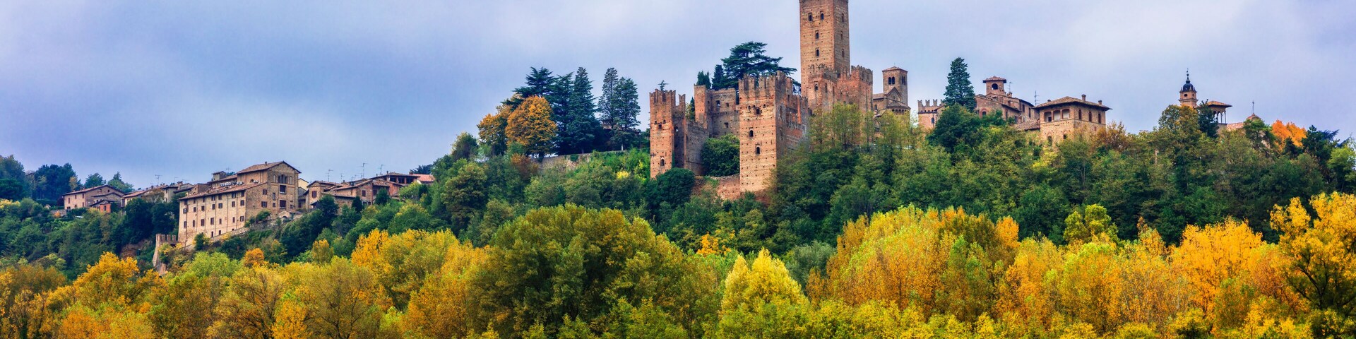 A historic castle on a hill surrounded by autumn-colored trees.
