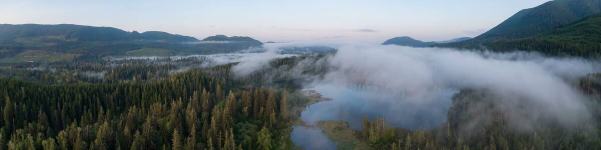 Aerial Panoramic View of Fairy Lake covered in clouds during a vibrant summer sunrise. Taken near Port Renfrew, Vancouver Island, British Columbia, Canada.