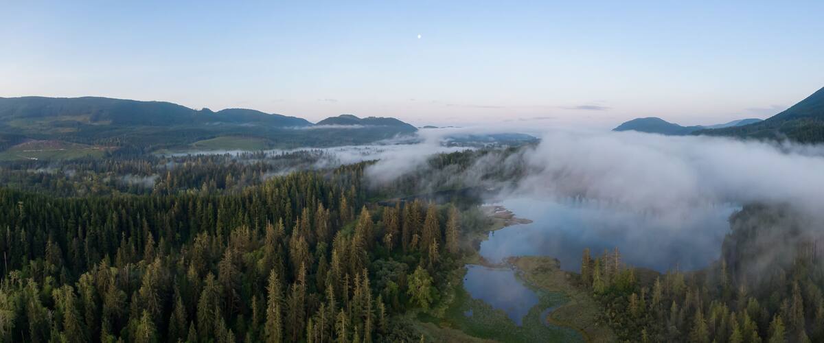Aerial Panoramic View of Fairy Lake covered in clouds during a vibrant summer sunrise. Taken near Port Renfrew, Vancouver Island, British Columbia, Canada.
