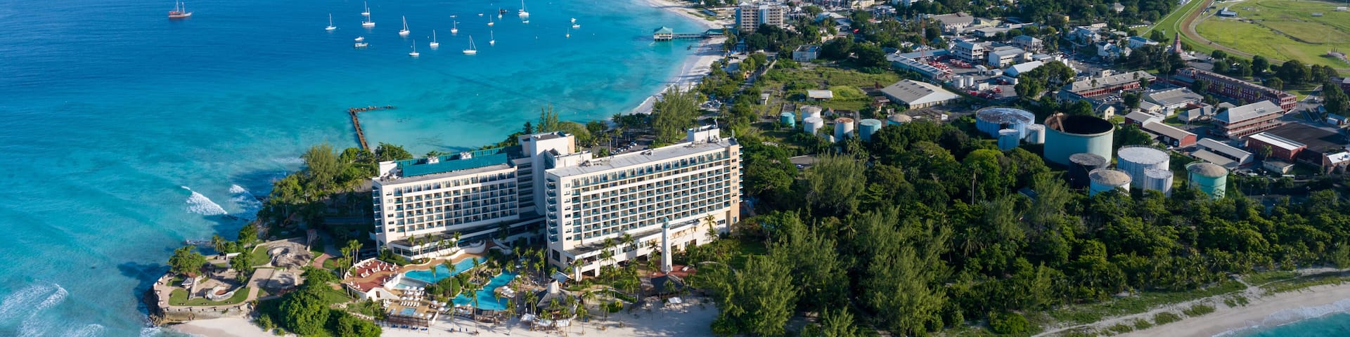 An aerial view of a coastal resort with a large hotel, beach, and marina.