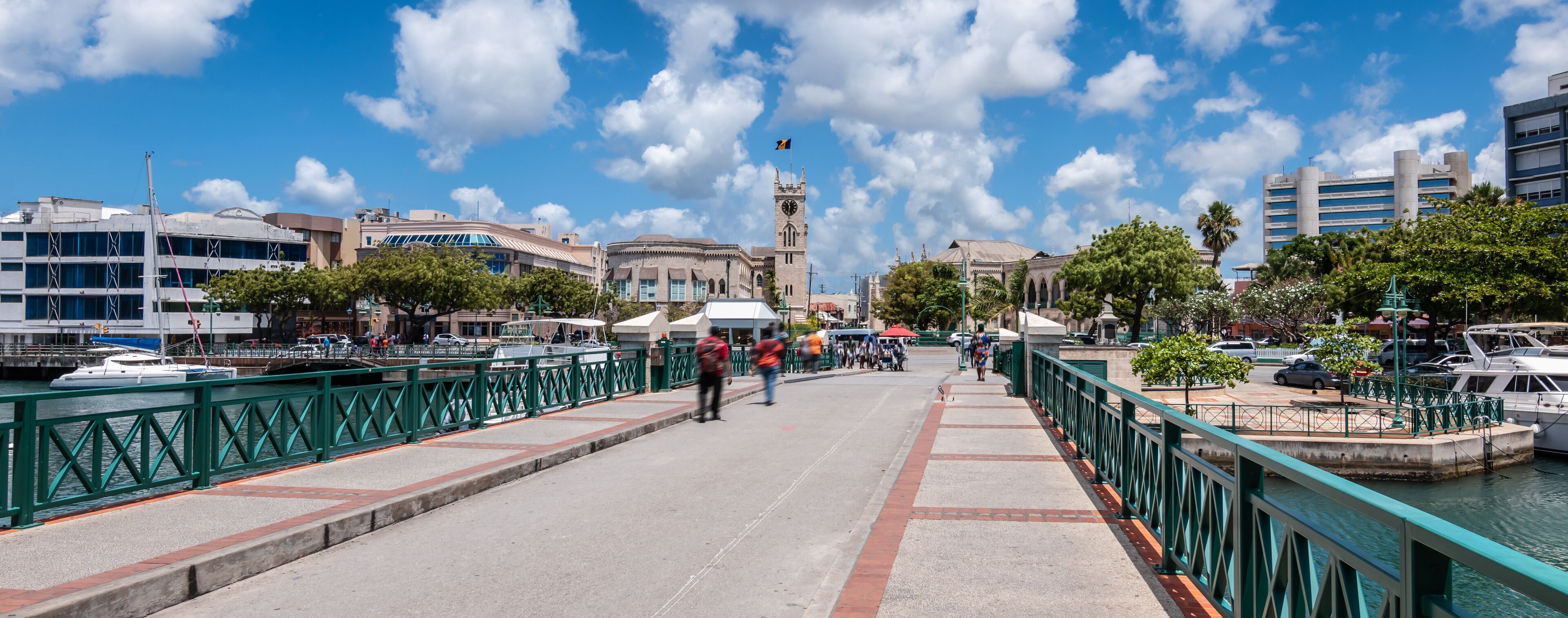 A waterfront promenade with boats, a bridge, and historic buildings.