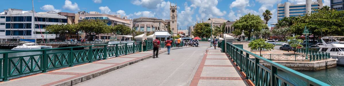 A waterfront promenade with boats, a bridge, and historic buildings.