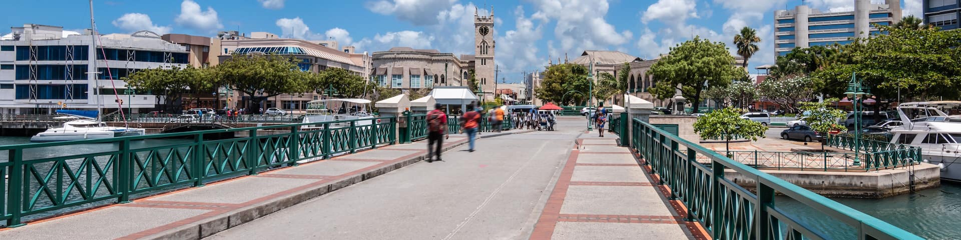 A waterfront promenade with boats, a bridge, and historic buildings.