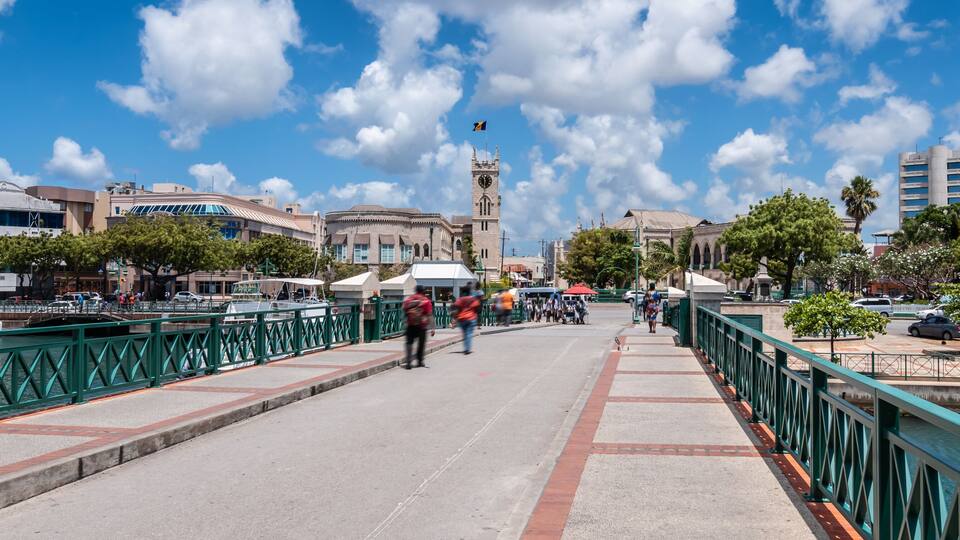 A waterfront promenade with boats, a bridge, and historic buildings.