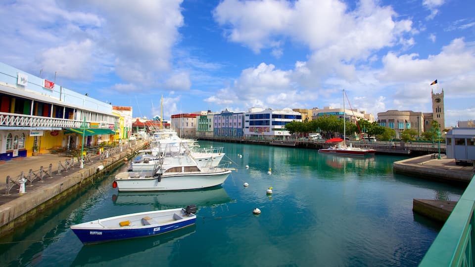A marina with boats docked, a clock tower, and colorful buildings along the waterfront.