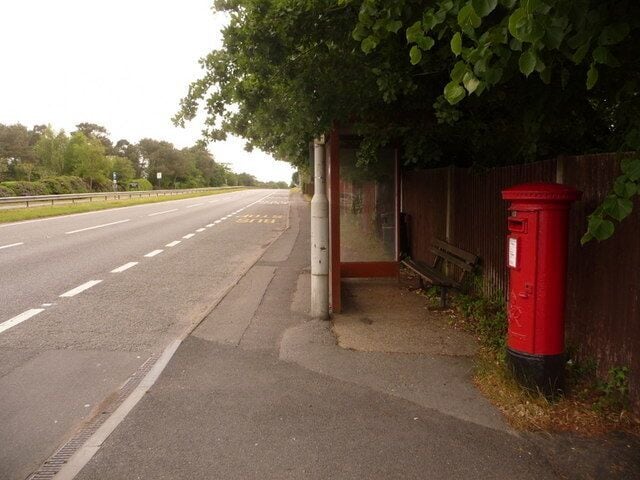 St. Leonards: postbox № BH24 45, Ringwood Road This George VI-reign postbox stands outside what was St. Leonards post office until about 20 years ago. It is emptied at 9am daily except Sundays. Meanwhile, we look along the north/eastbound carriageway of the main A31 in a rare moment with no visible traffic.