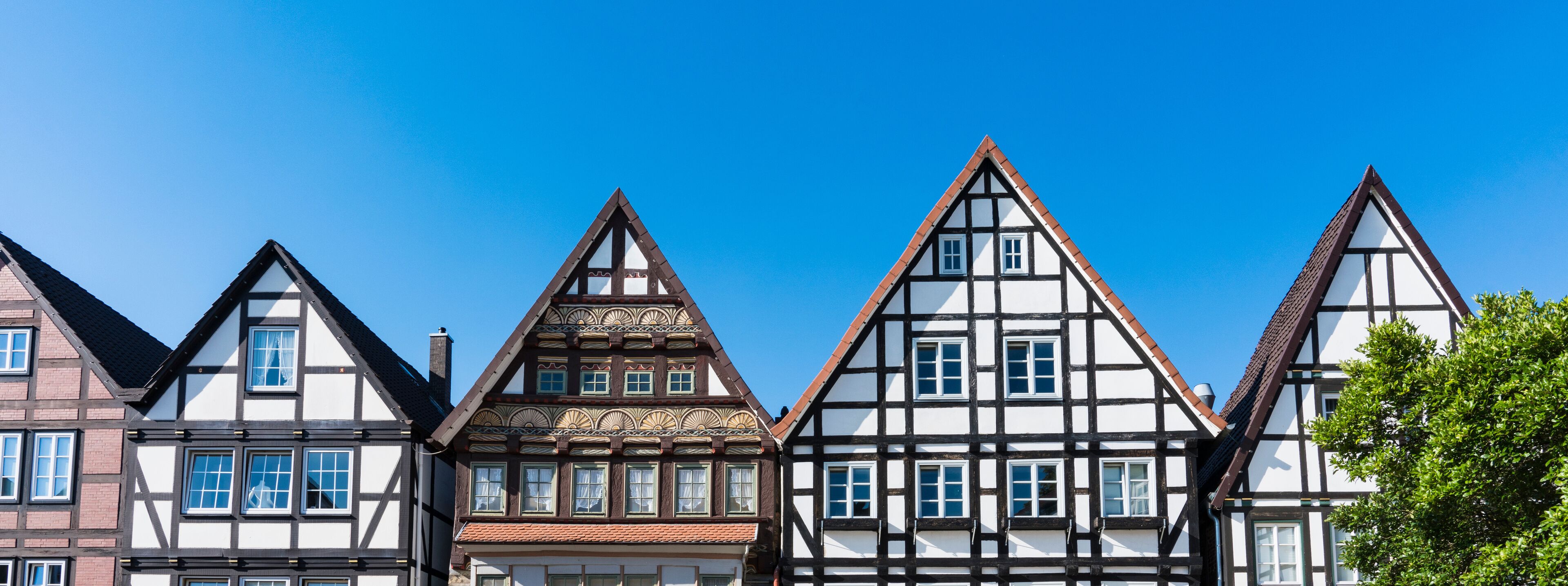 A row of traditional half-timbered houses with steeply pitched roofs and white facades.