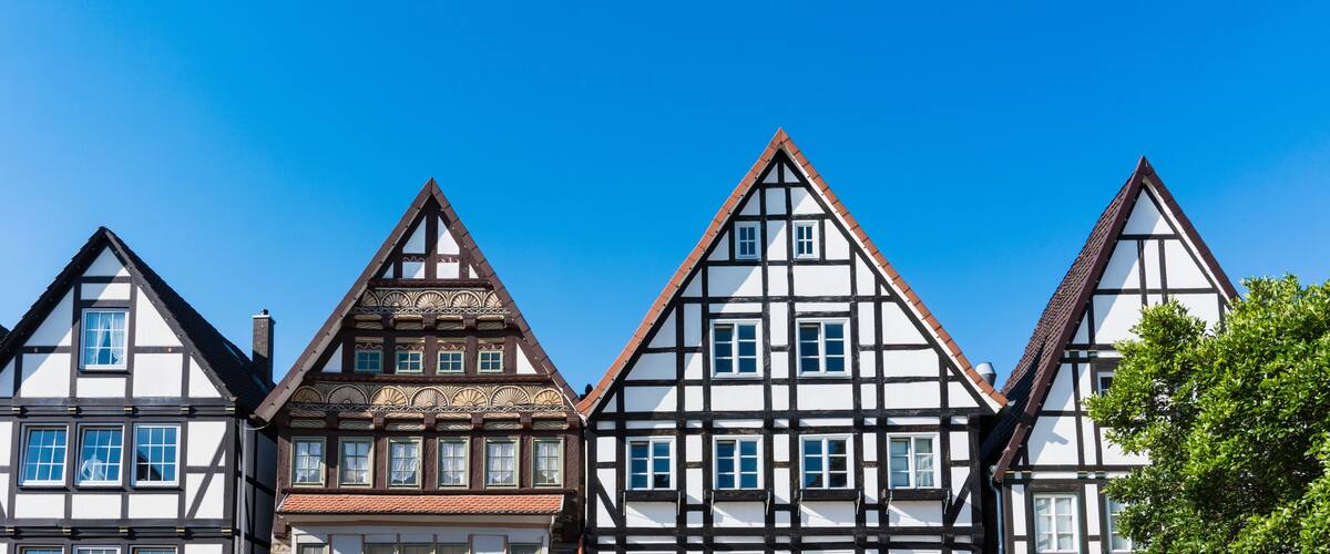 A row of traditional half-timbered houses with steeply pitched roofs and white facades.