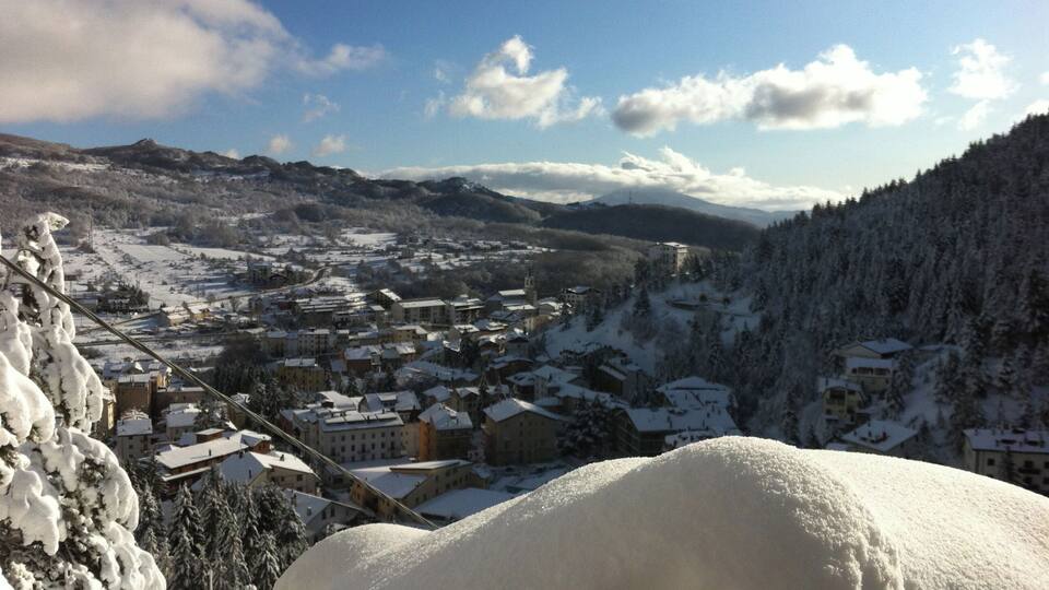 A snow-covered village with buildings and mountains in the background.