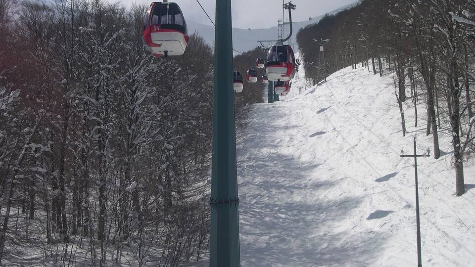 A ski lift with two cabins ascending a snowy slope.