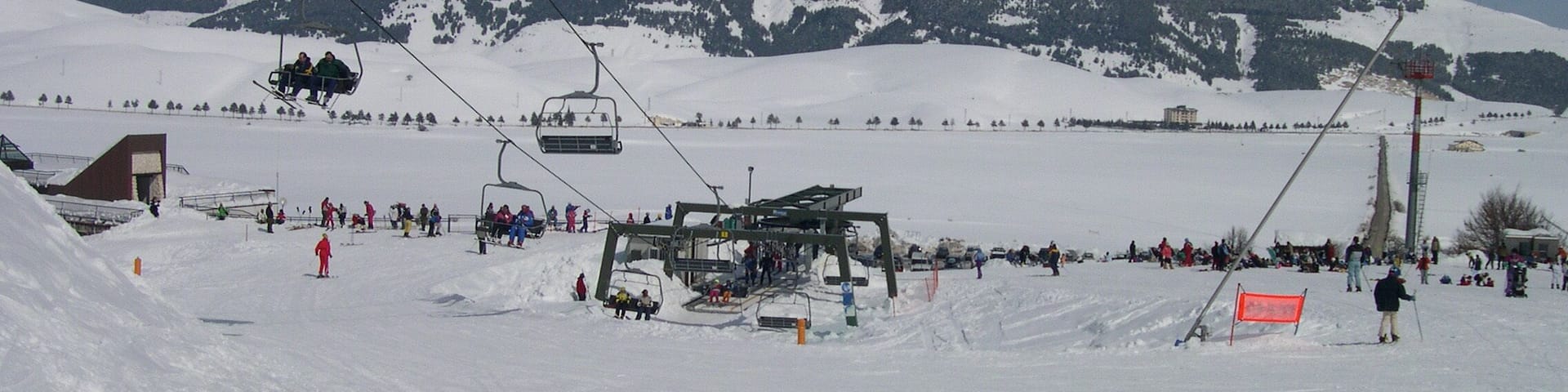 A snowy ski slope with ski lifts and skiers.