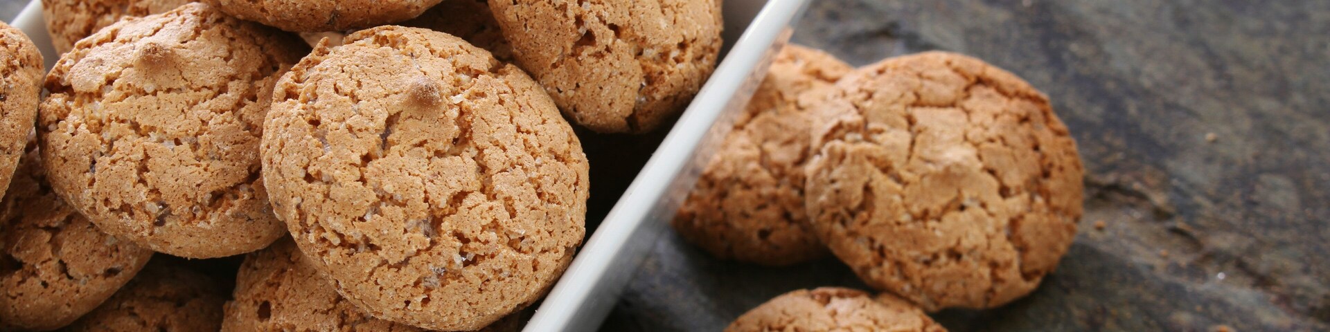 A white bowl filled with round, textured cookies on a dark surface.
