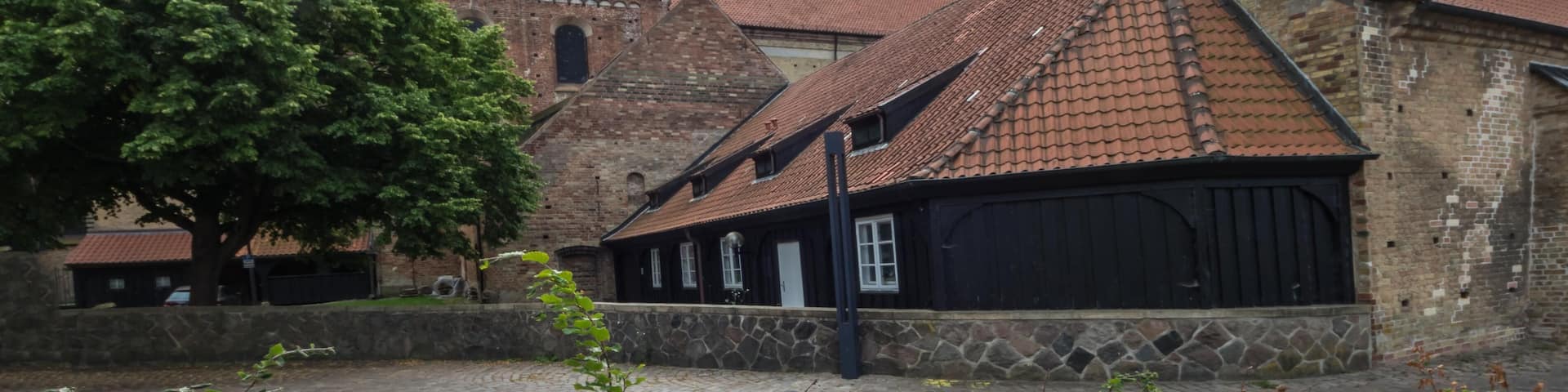A historic church with two tall spires and a brick building with a tiled roof.