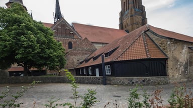 Uma igreja histórica com duas torres altas e um edifício de tijolos com telhado em telhas.