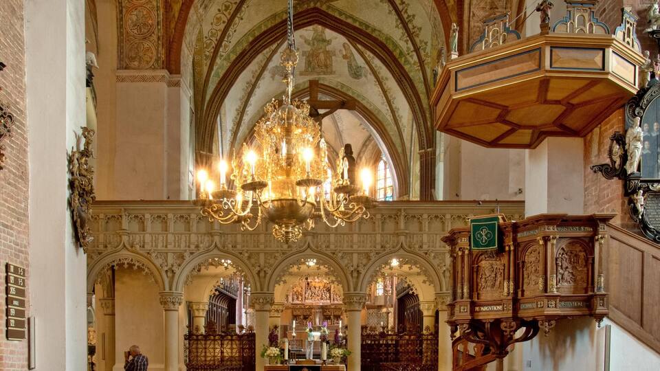 An interior of a church with wooden pews, a chandelier, and a high vaulted ceiling with intricate designs.