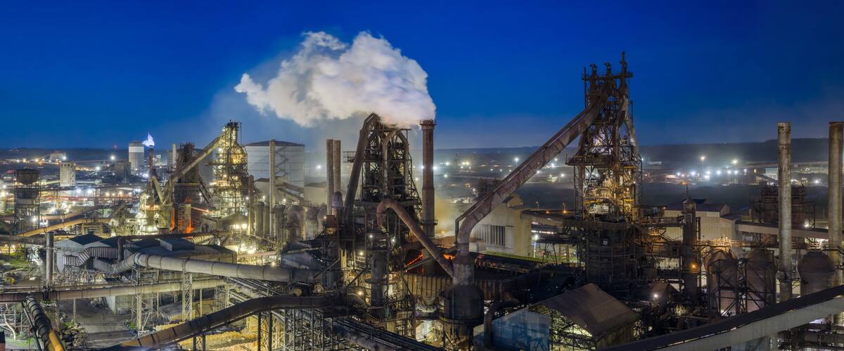 An industrial complex with multiple smokestacks, large processing towers, and extensive piping networks.