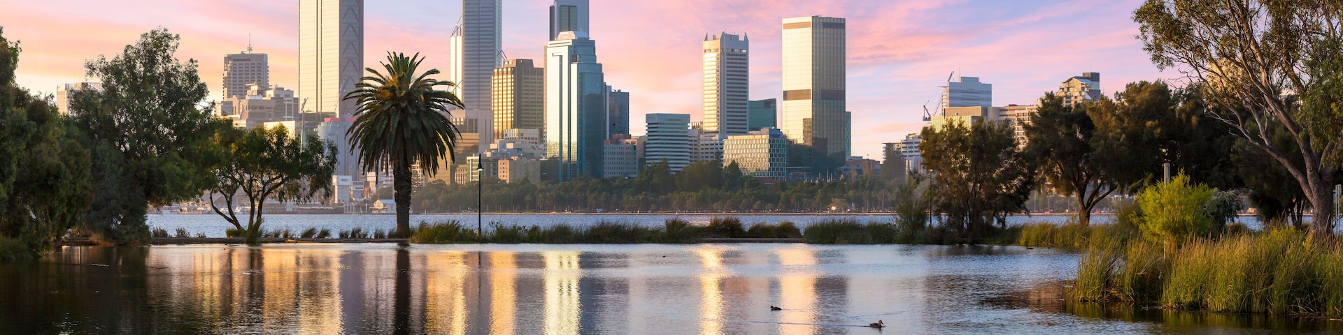 Un horizonte urbano con rascacielos modernos y un lago tranquilo que refleja los edificios.