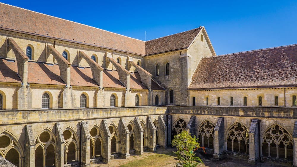 Un bâtiment historique doté d’une cour intérieure, de passages voûtés et d’un toit recouvert de tuiles.