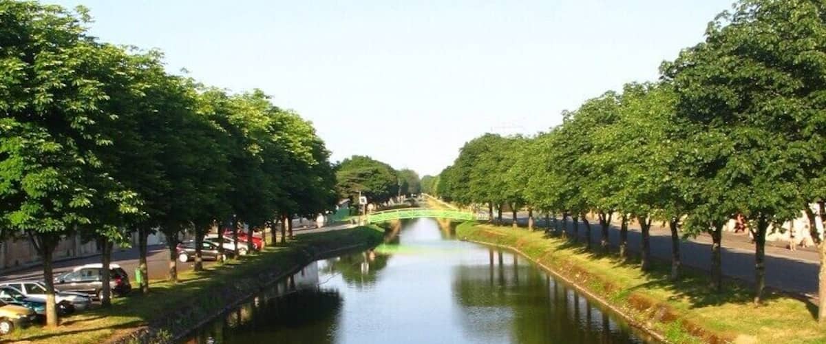 Canal de Berry à Saint-Amand Montrond, Cher, vue O-E. Aménagé entre début et mi-XIXe s. au petit gabarit berrichon (27,5 x 2,6 m, port max. 60 t), il est déclassé en 1955. On est loin des dimensions Freycinet, 38,5 x 5,05 m, port de 250 à 400 t, normes d’une grande part du réseau fluvial français, un peu plus tard ! Ses 3 branches cumulées, représentent 320 km de voies d’eau. Celle traversant la ville, dite sud et qui opère un large coude, vient de Montluçon, Allier.