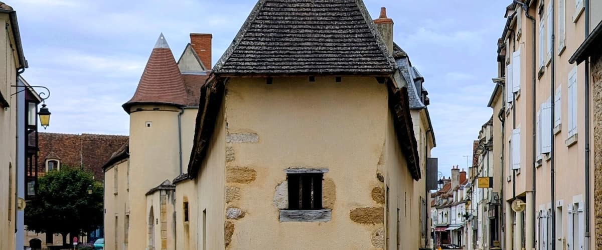 A cobblestone street leading to a small stone building with a triangular roof.