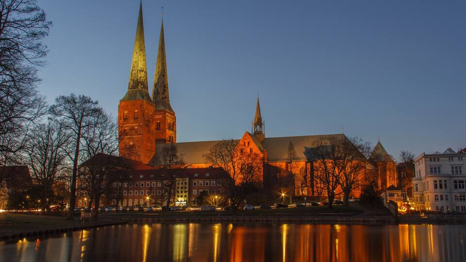 A historic church with two spires and a reflection in the water.