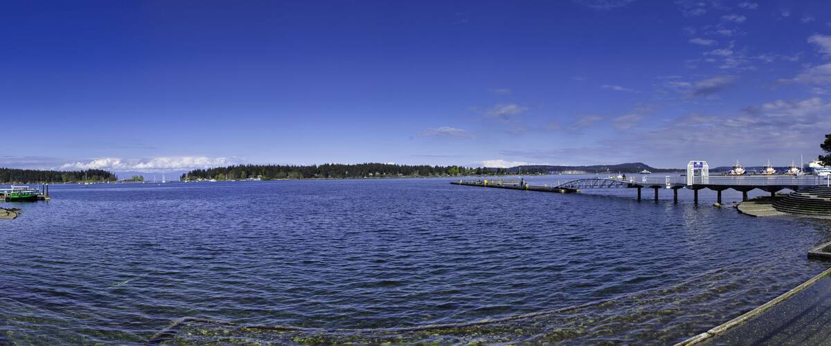 A calm lake with a pier and a bridge.