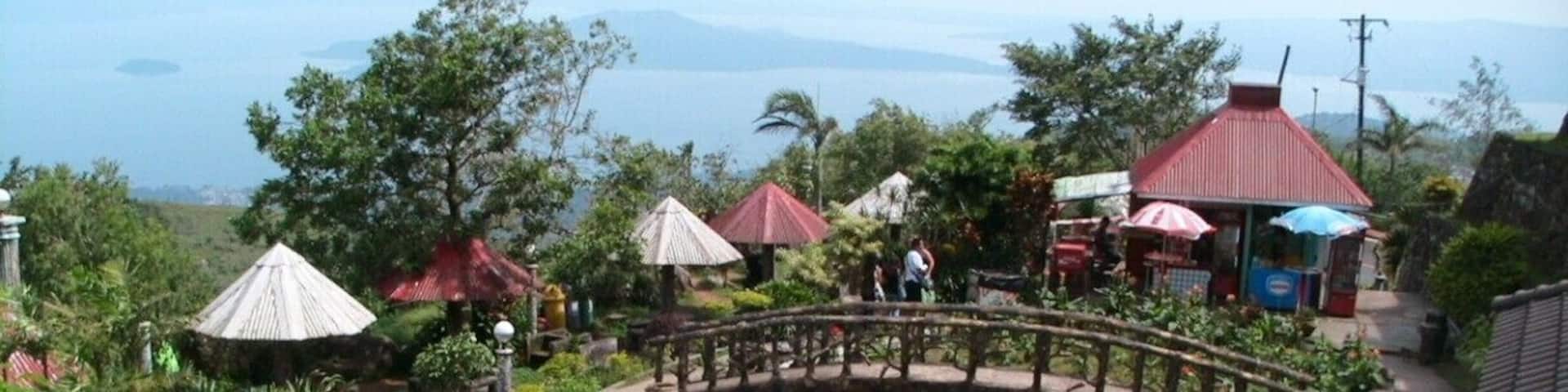 Un jardin avec un sentier sinueux, des constructions aux toits rouges et une vue sur la mer.