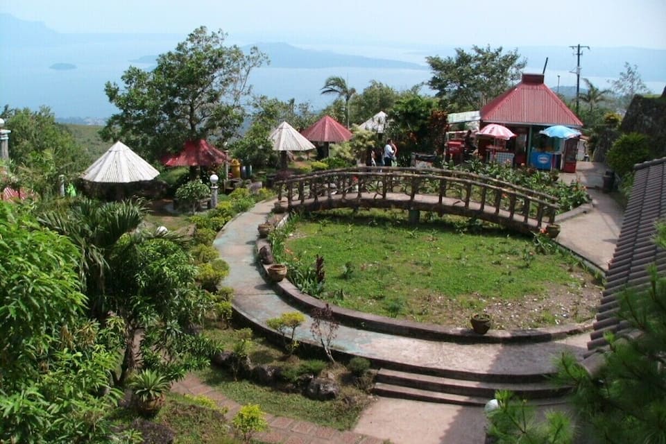 A garden with a curved pathway, red-roofed structures, and a view of the sea.