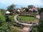 A garden with a curved pathway, red-roofed structures, and a view of the sea.