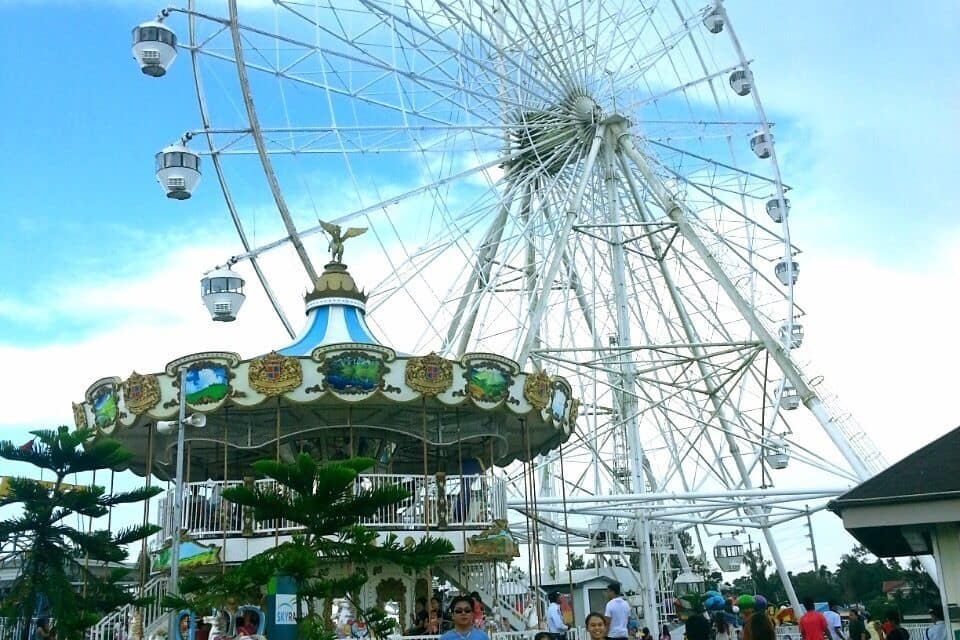 Uma roda gigante grande com um carrossel na frente.