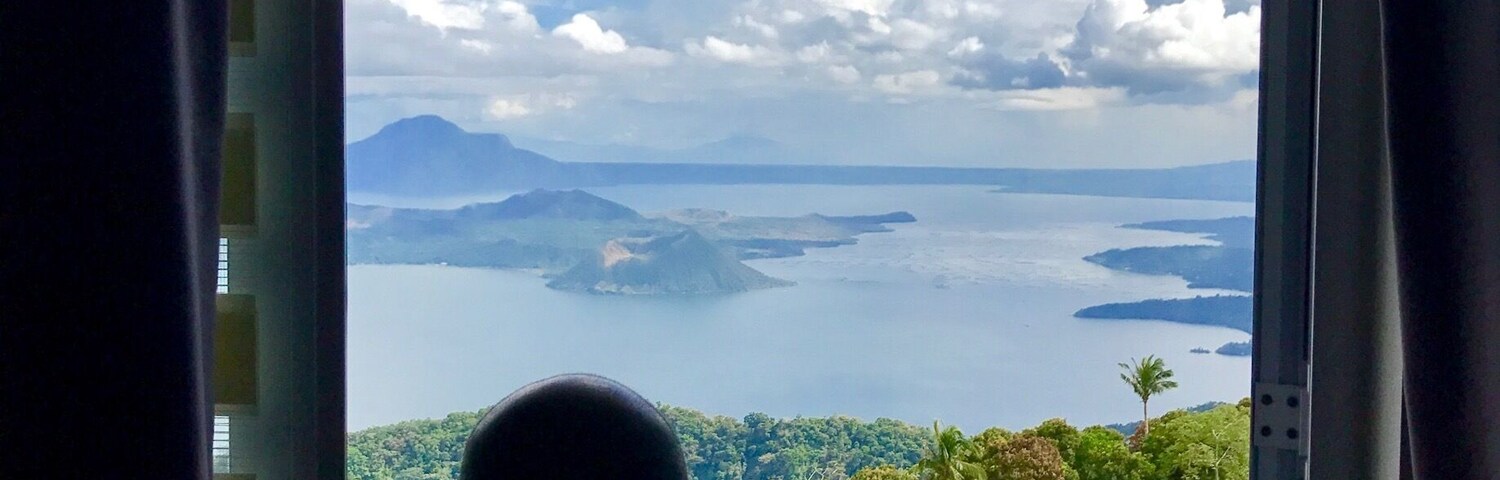 A person overlooking a scenic view of a coastline with mountains and a body of water.