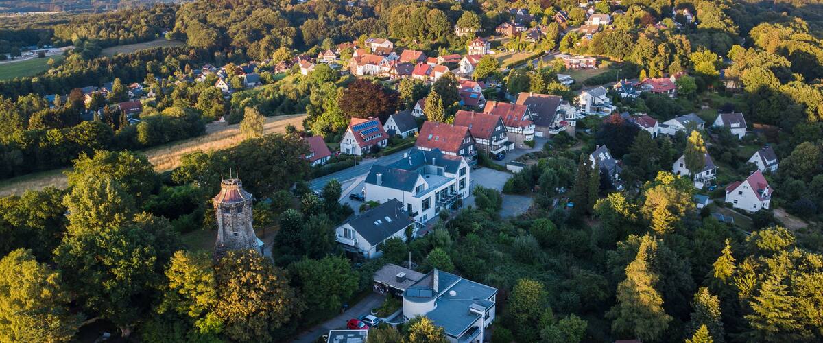 An aerial view of a village with houses, a church, and surrounding greenery.