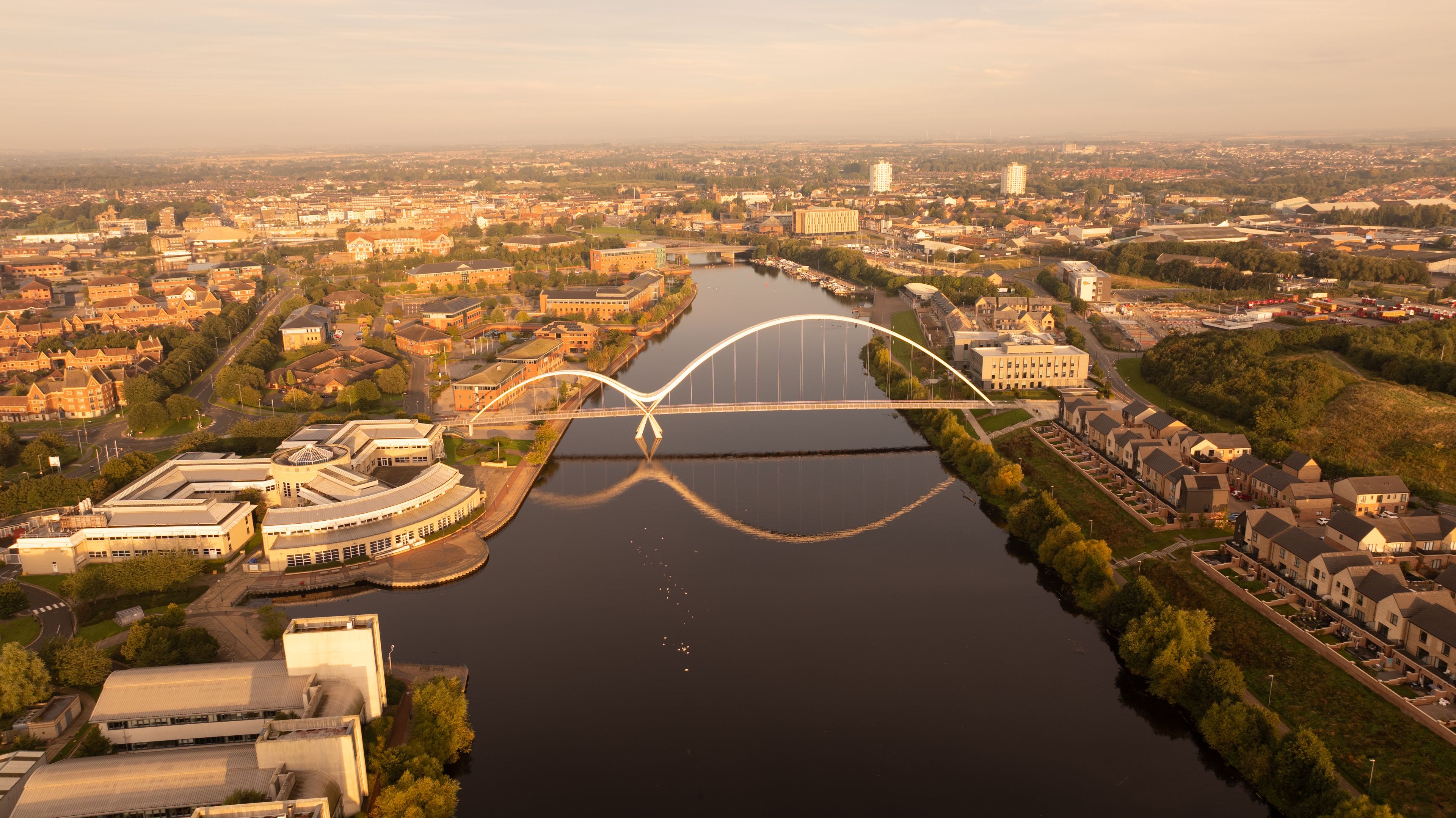 A river with a bridge, buildings, and greenery.