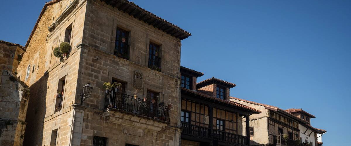 A cobblestone street lined with historic stone buildings featuring balconies and arched doorways.