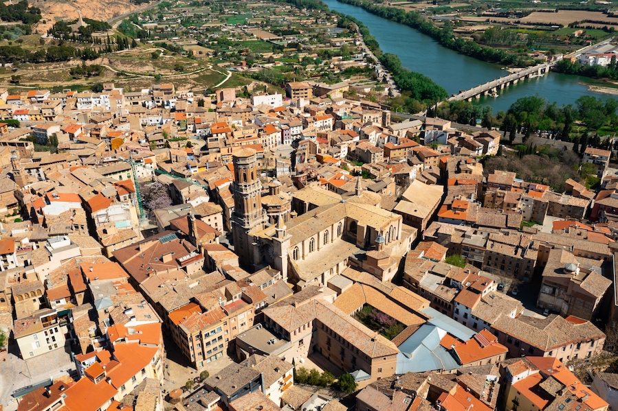 A densely packed urban area with historic architecture, a prominent church tower, and a river running through the city.