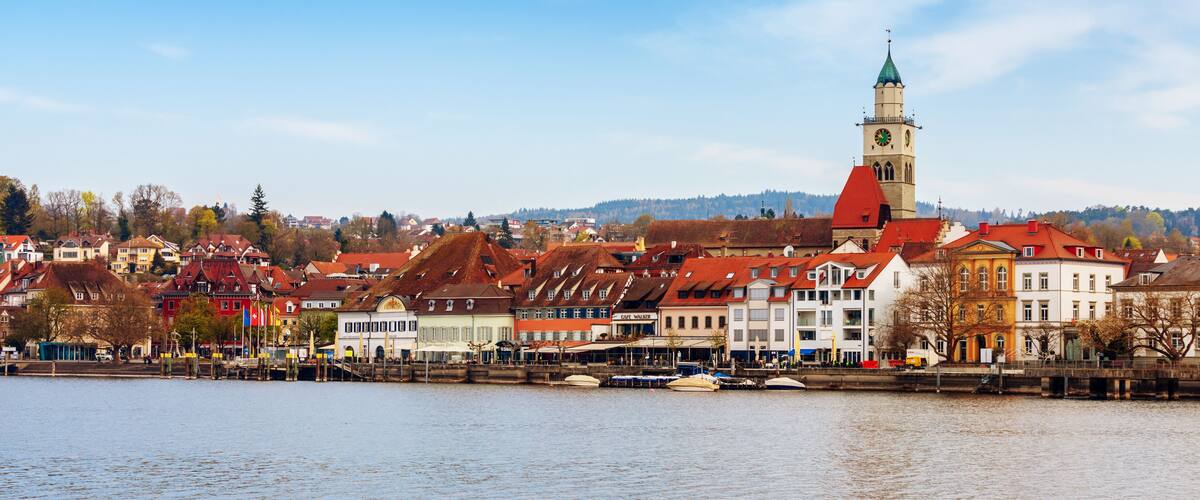 A riverside town with historic buildings and a prominent clock tower.