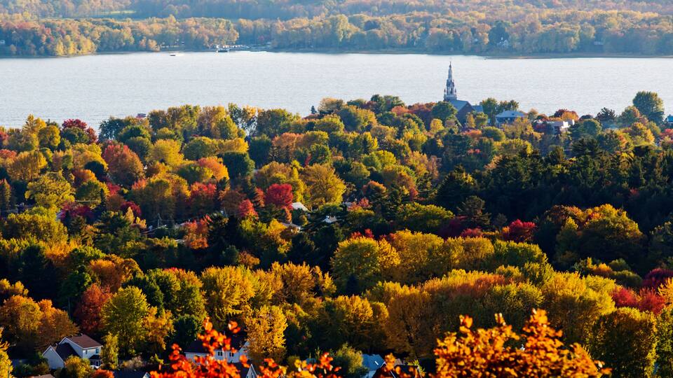 A lake surrounded by autumn-colored trees and houses.