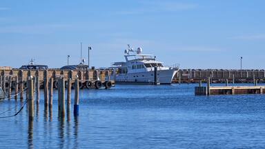 A large yacht docked at a pier with a clear blue sky in the background.