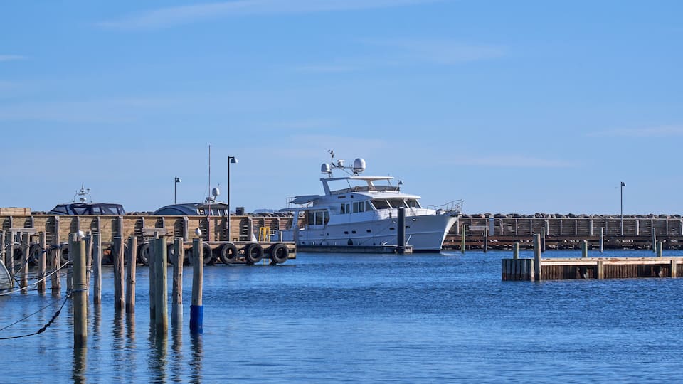 A large yacht docked at a pier with a clear blue sky in the background.