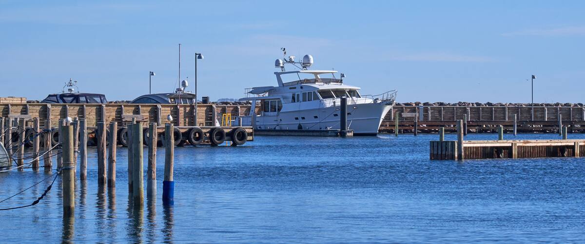 A large yacht docked at a pier with a clear blue sky in the background.