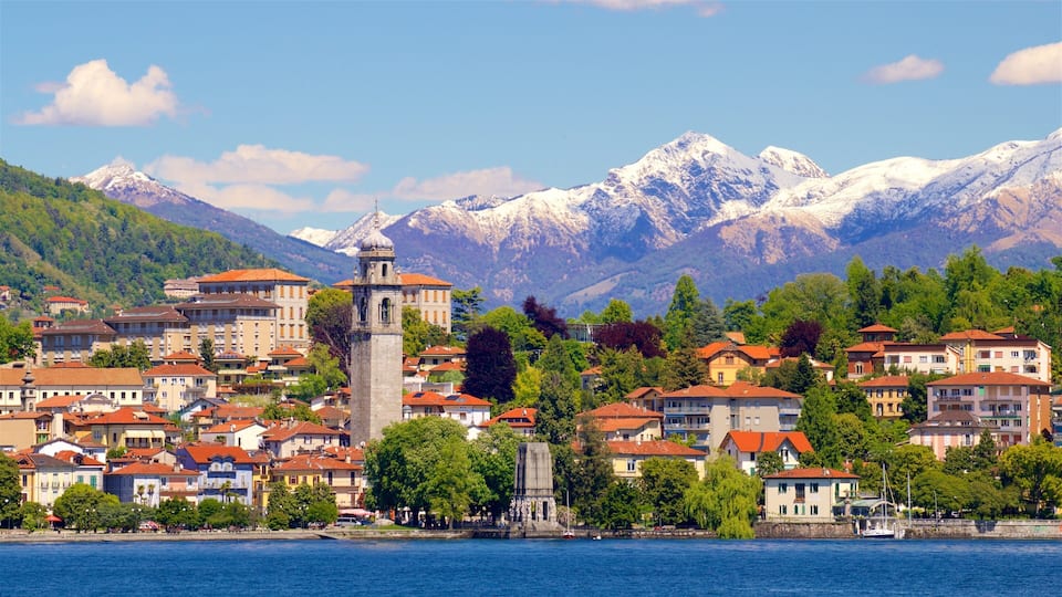 A coastal town with a prominent tower, surrounded by colorful buildings and snow-capped mountains in the background.