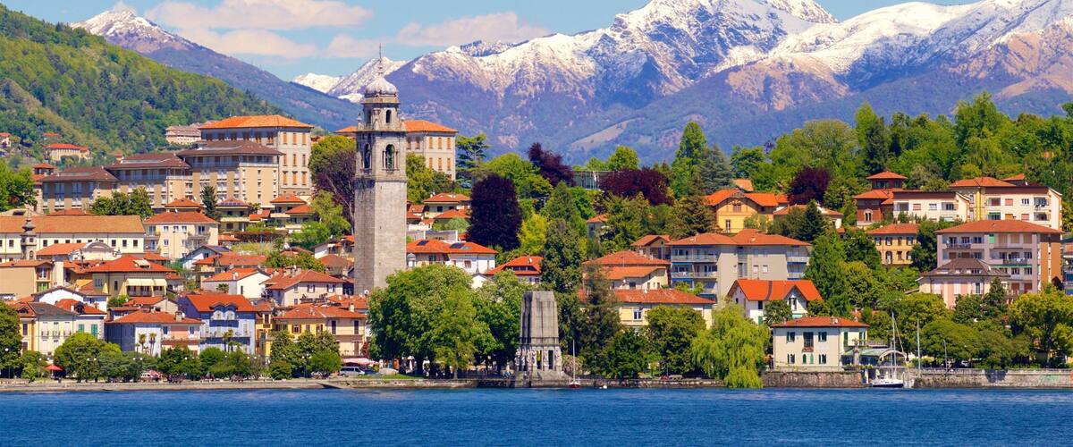 A coastal town with a prominent tower, surrounded by colorful buildings and snow-capped mountains in the background.