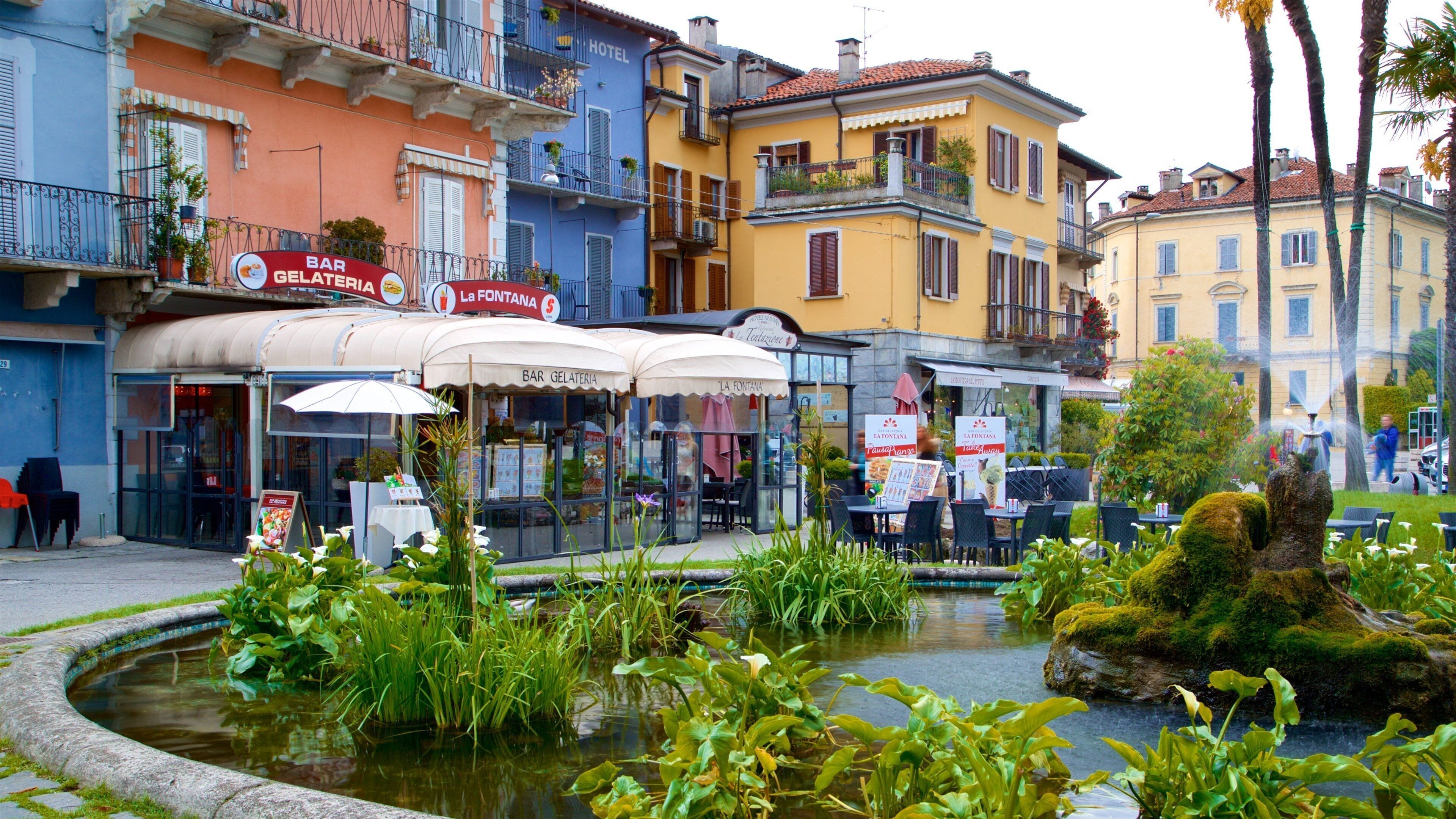 A European street with gelateria bars, outdoor seating, and a fountain.