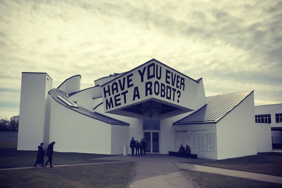 Un edificio moderno con un grande cartello che chiede: "Hai mai incontrato un robot?"
