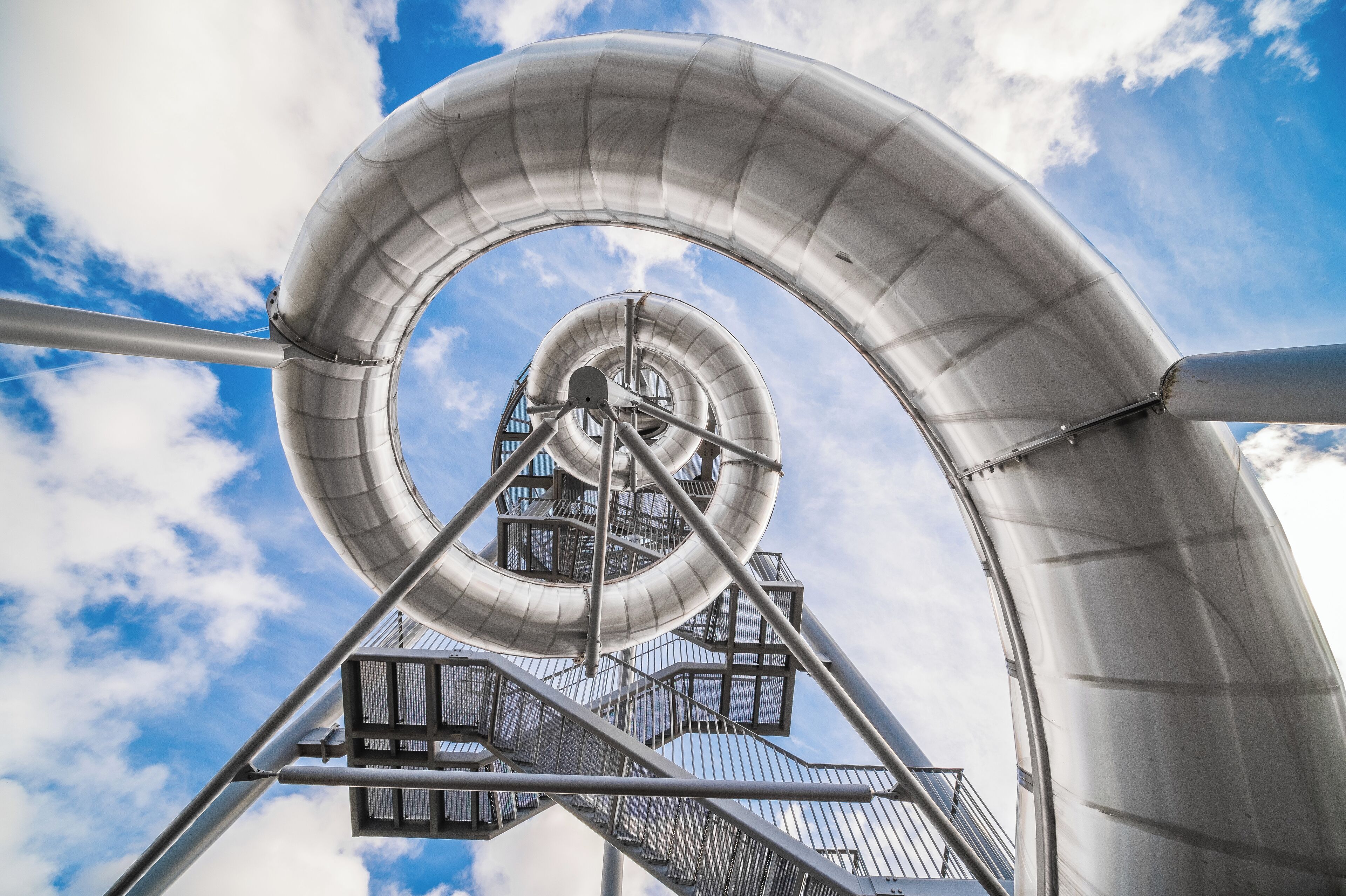 A spiral structure against a blue sky with clouds.
