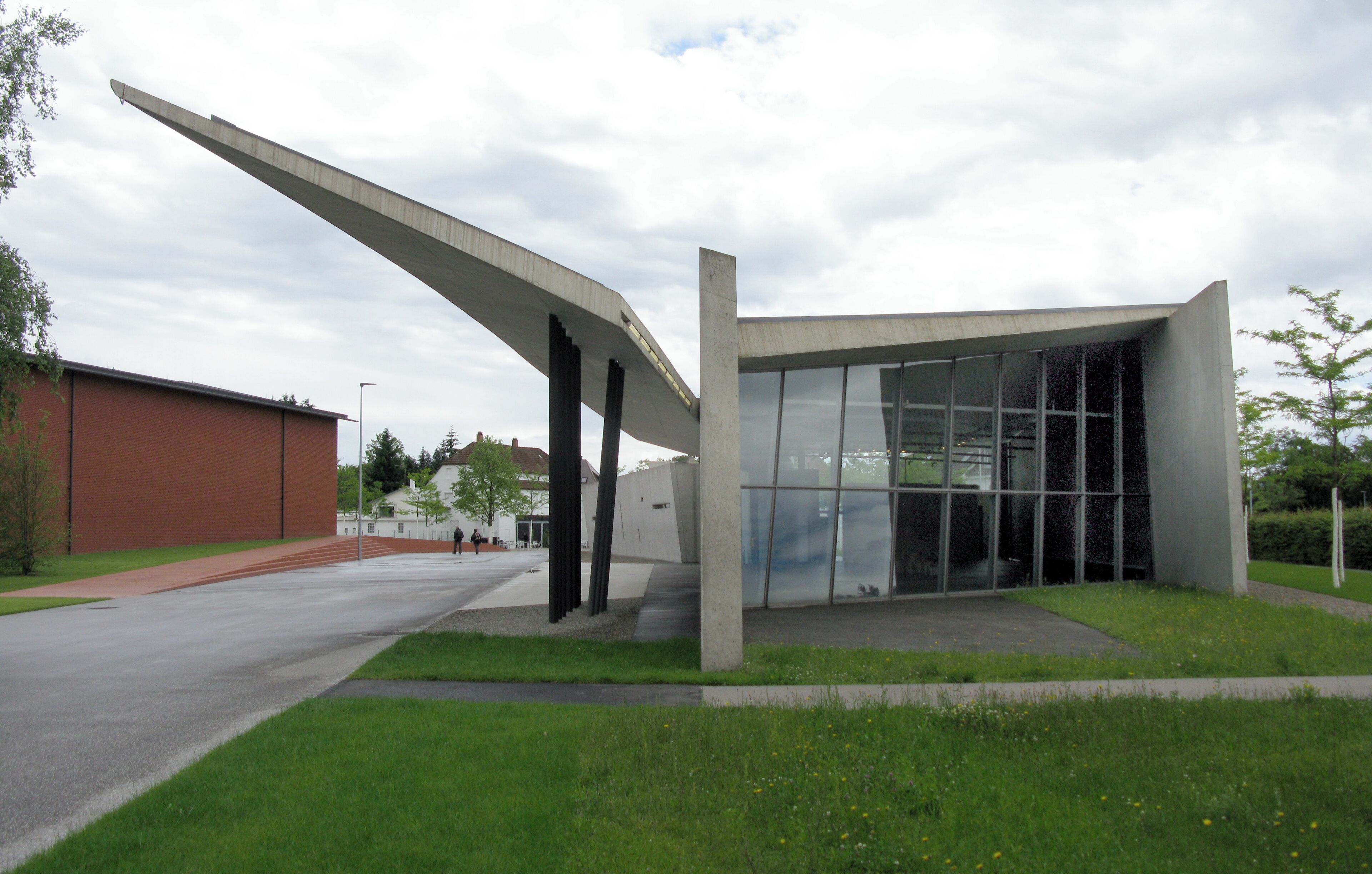 A modern building with a unique curved roof structure and large glass windows.