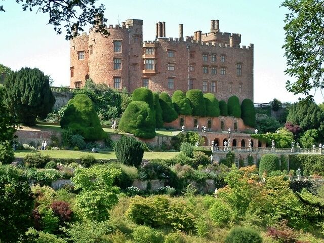 A castle with a well-maintained garden and a bridge.
