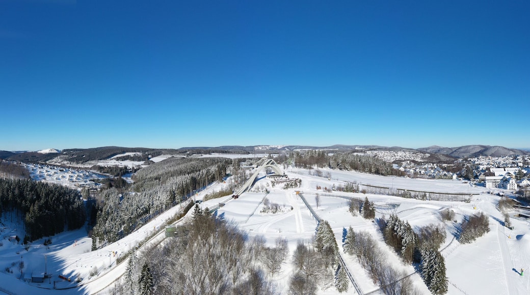 Saint George ski jump and ski slopes of Winterberg ski lift carousel photographed from the air. Panorama image of deserted winter sports area.